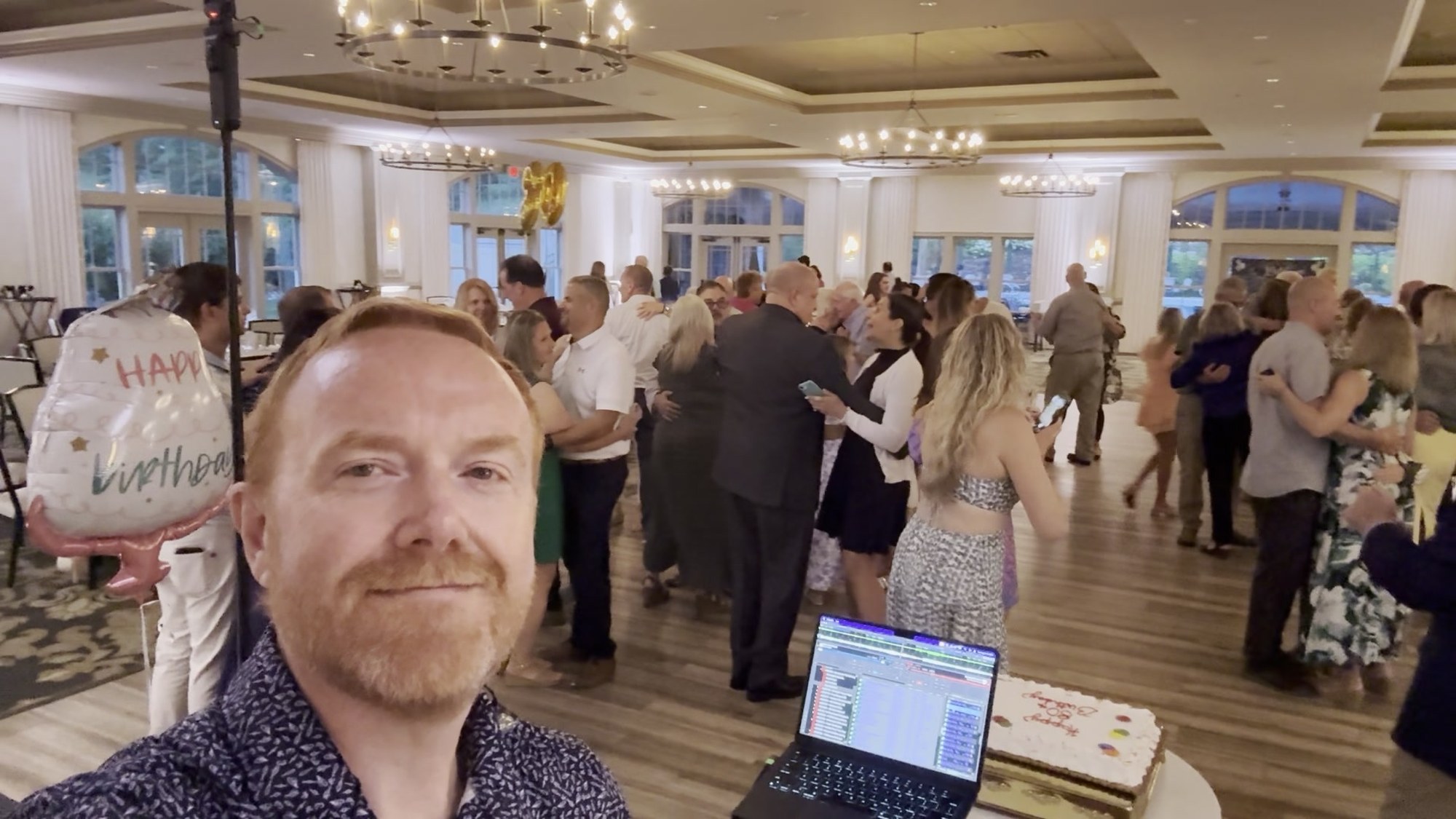 James of Gingerbeard Events smiling with an active dance floor behind him