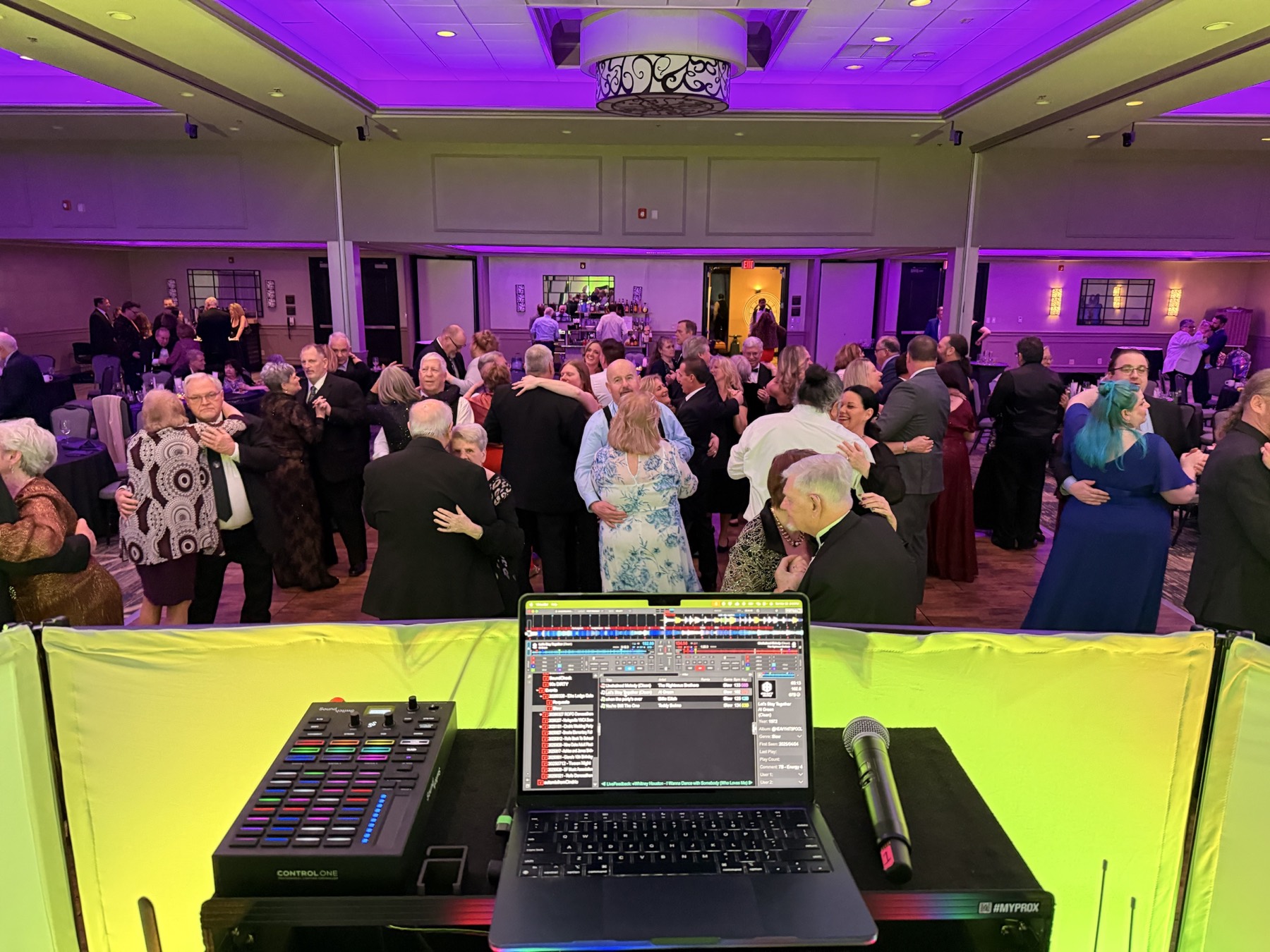 Guests dancing under purple lighting at a formal organization event